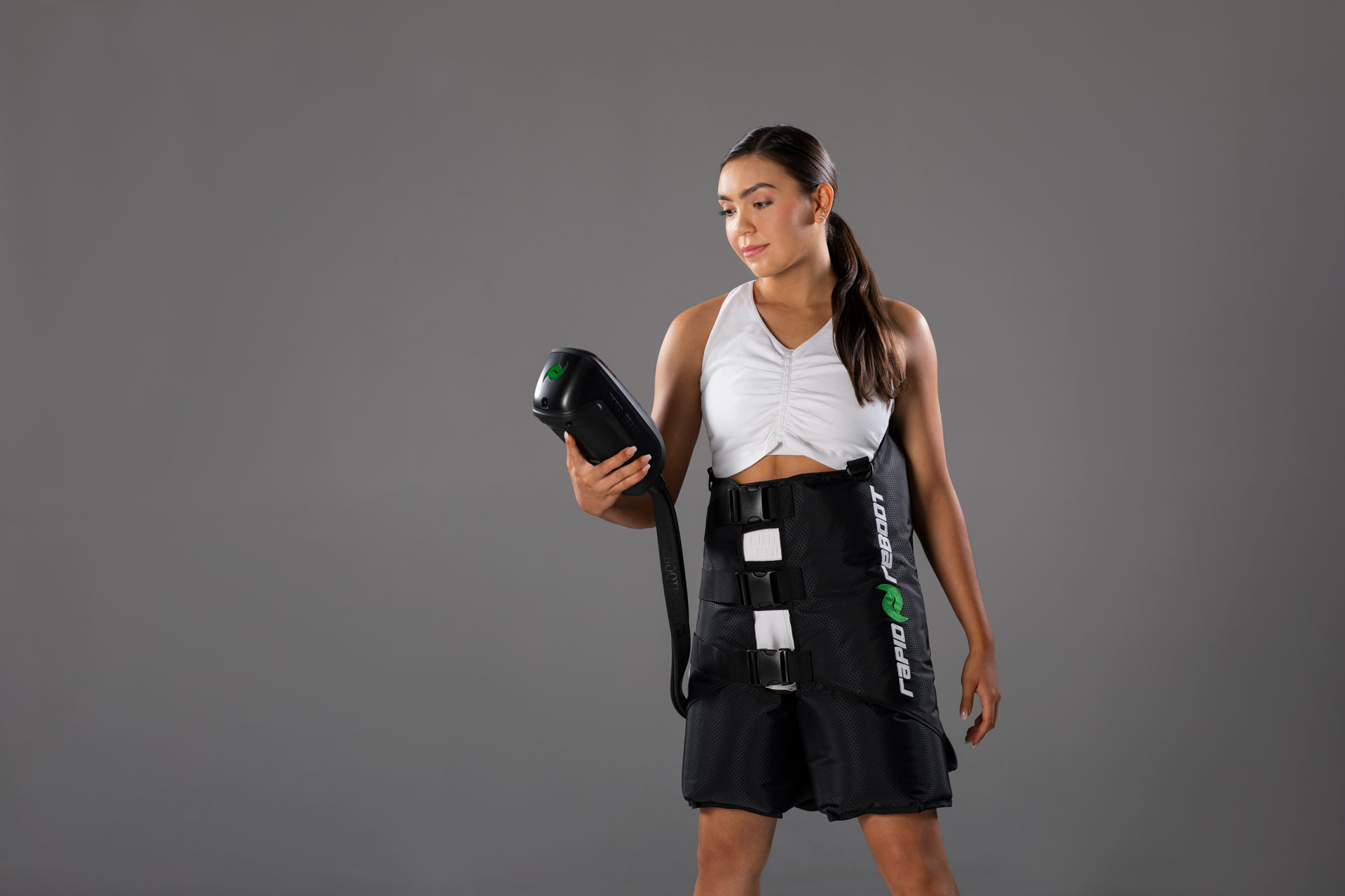 Athlete using Rapid Reboot REGEN compression boots with hip attachment in a relaxed home setting.